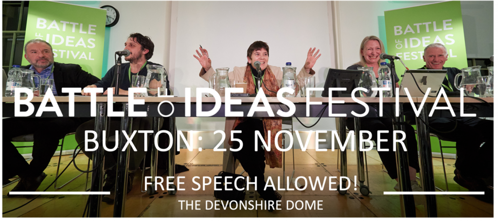 This image is of a 5 person panel at a Battle of Ideas debate. Claire Fox, the panel chair, site in the centre and has her arms raised as she enthusiastically addresses the audience.